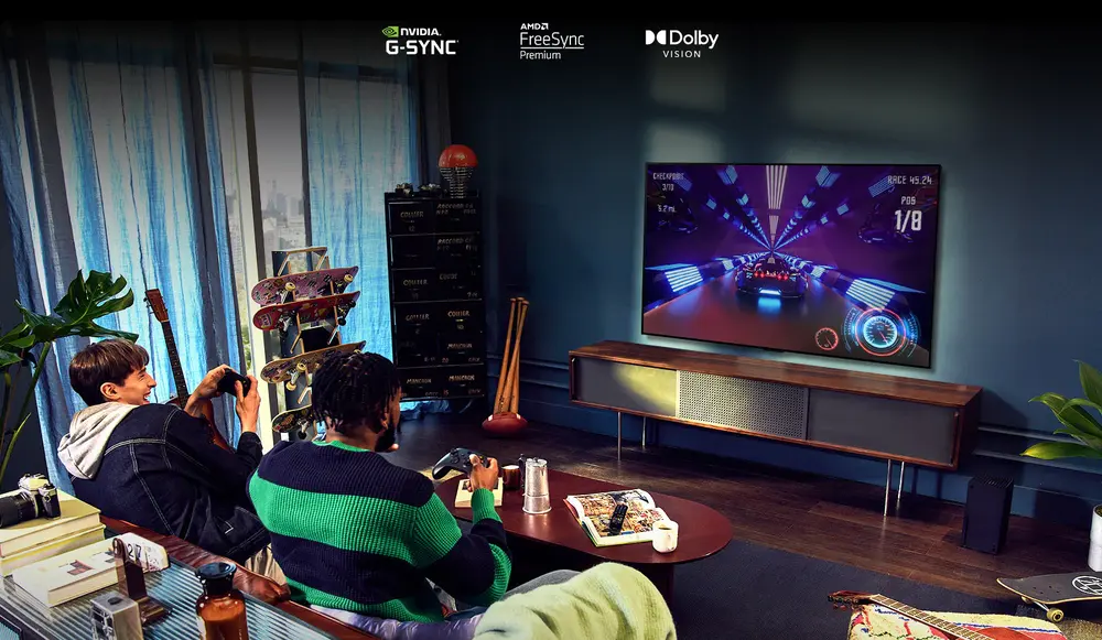 Doua persoane stau pe o canapea si se joaca un joc de curse cu o unitate de comanda si televizorul LG OLED G2 intr-o sufragerie