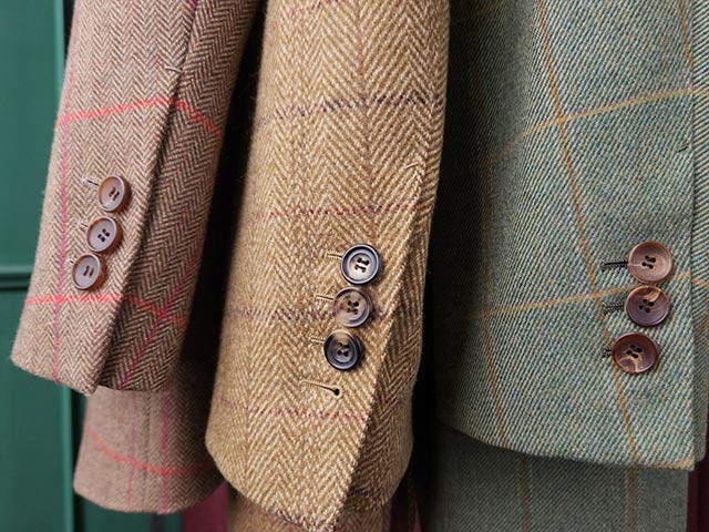 Trei jachete, in culori diferite, cu modele in carouri, sunt agatate una langa cealalta. Rezolutia inalta a fotografiei permite ca textura tesaturii sa fie vazuta clar.
