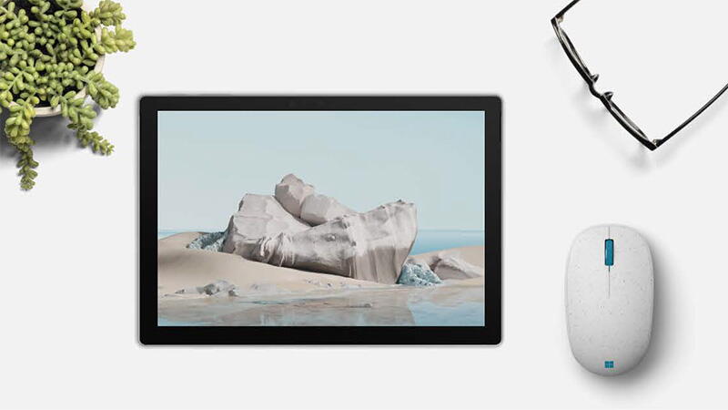O tableta cu un ocean pe ecran, langa Microsoft Ocean Plastic Mouse si o pereche de ochelari de citit