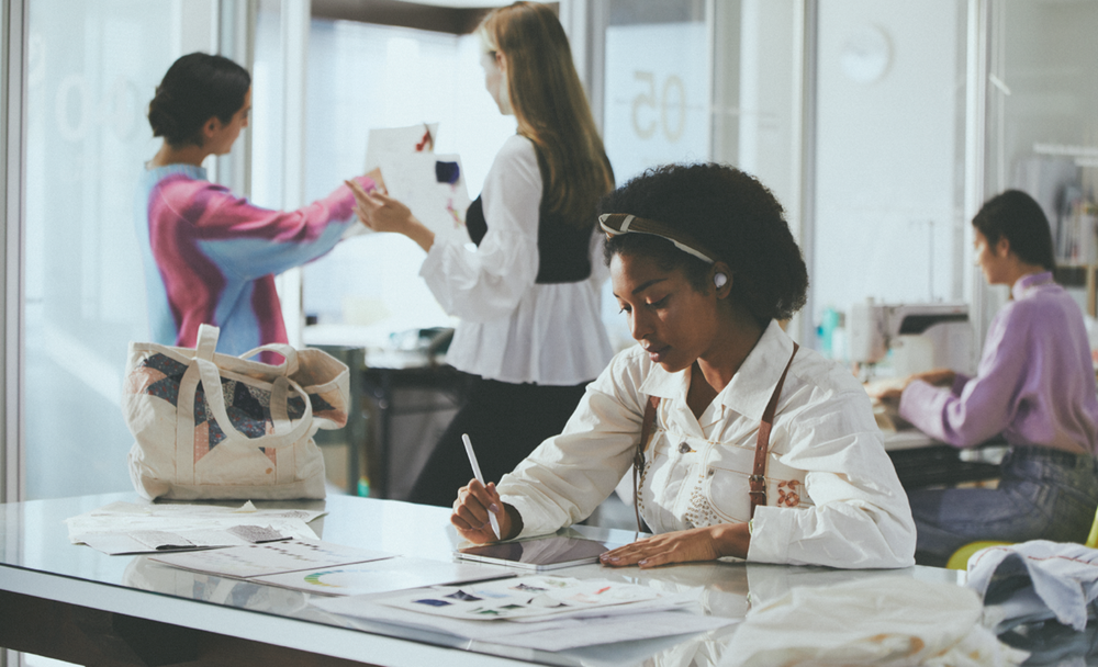 Imagine cu o femeie lucrand pe tableta, purtand casti wireless WF-C700N cu anulare digitala a zgomotului intr-un birou aglomerat