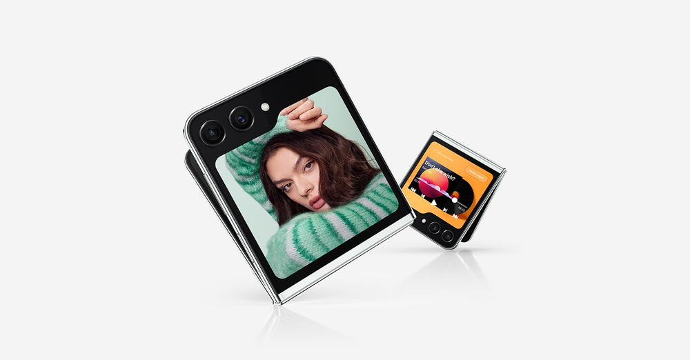 Zwei leicht aufgeklappte Galaxy Z Flip5 Geräte mit Flex Windows. Auf dem einen ist ein Selfie zu sehen. Das zweite Flex Window zeigt einen Media-Player mit Wiedergabesteuerung und Ladebalken.